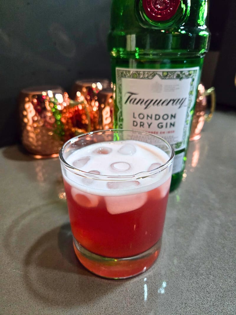 Cocktail on the bar at Club X Indoor Golf — Tanqueray and a fresh-poured red cocktail under warm bar lighting