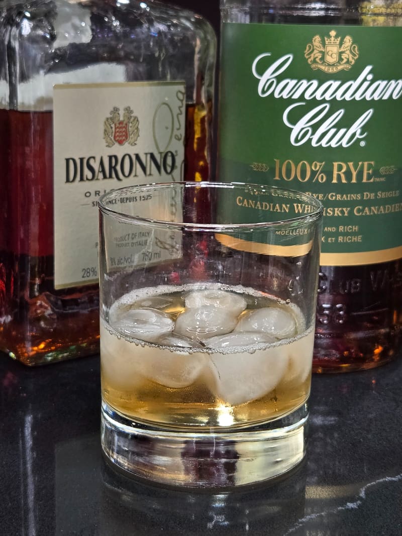 Bar at Club X Indoor Golf — Disaronno, Canadian Club, and a rocks glass under warm bar lighting