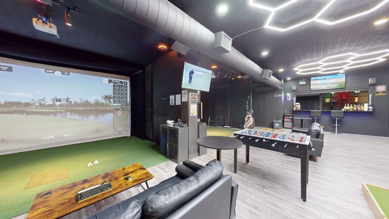 Indoor golf simulator bay at Club X Indoor Golf in Aurora with lounge seating and TrackMan setup