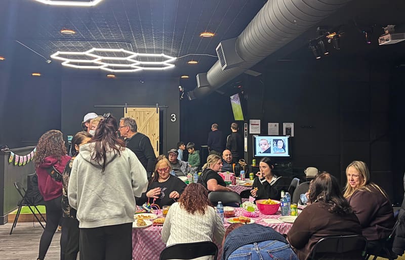 Private friend-group event at Club X Indoor Golf — adults seated at tables under the hex-lit ceiling